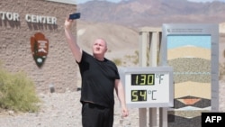 Scott Hughes, of Swansea, Wales, UK, takes a selfie next to a digital display of an unofficial heat reading at Furnace Creek Visitor Center during a heat wave in Death Valley National Park in Death Valley, California, on July 16, 2023. (Photo by Ronda Churchill / AFP)