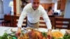 Esdras Zayas places the Thanksgiving turkey on the dining room table before his family celebrates their first holiday without their beloved mother Ana Martinez who died at 78 on April 1 while recovering at a nursing home from a knee replacement,…