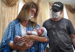 Argentinian Andrea Viez and her husband react as they collect their son in the hotel Venice in the Ukrainian capital of Kiev on June 10, 2020.