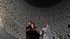 Visitors look at a wall displaying the names of the victims of 2004 Indian Ocean tsunami, at the Tsunami Museum in Banda Aceh, Aceh province, Indonesia, Dec 14, 2024. 