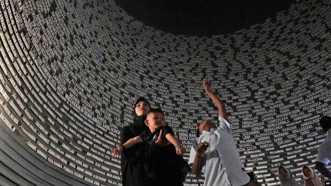 Visitors look at a wall displaying the names of the victims of 2004 Indian Ocean tsunami, at the Tsunami Museum in Banda Aceh, Aceh province, Indonesia, Dec 14, 2024. 
