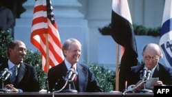 ARCHIVO - El presidente egipcio Anwar al-Sadat y el presidente estadounidense Jimmy Carter se ríen durante el discurso del primer ministro israelí Menachem Begin, antes de firmar el Acuerdo de Paz entre Israel y Egipto el 26 de marzo de 1979 en la Casa Blanca.