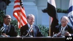 Jimmy Carter i predsednik Egipta, Anwar al-Sadat, osmjehuju se tokom govora izraelskog premijera Menachem Begin, pred postpisivanje mirovnog sporazuma između Izraela i Egipta 26. marta 1979. godine u Bijeloj kući. (Foto: AFP)