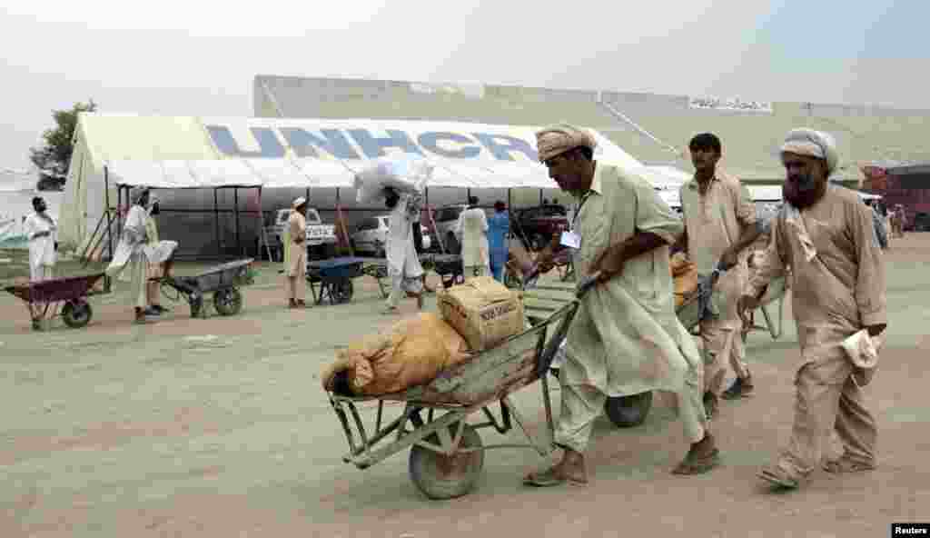 Un ouvrier pousse une brouette contenant l&#39;aide pour les déplacés à l&#39;intérieur d&#39;un centre de distribution alimentaire dans un stade à Bannu, dans le nord-Pakistan, le 25 Juillet 2014. 