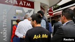 A man makes a transaction at an ATM outside a branch of Laiki Bank in Nicosia, March 21, 2013.