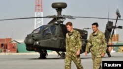 Pangeran Harry berjalan melewati helikopter Apache di Camp Bastion, Afghanistan 7 September 2012. (Foto: REUTER/John Stillwell/POOL)