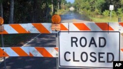 A sign stands near the Carter's Crossroads community in Georgetown County, a road adjacent to Boser Swamp is flooded over, Wednesday, Sept. 26, 2018, in Georgetown County, S.C. This is one of many lowlying areas in this and other nearby farming communities where roads are blocked off days after the rains of Florence have stopped. 