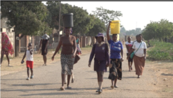 Women carry buckets of water from an open well, in Harare, Sept. 23, 2019. (C.Mavhunga/VOA)