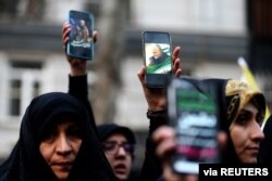 Para demonstran Iran mengacungkan ponsel dengan gambar mendiang MayjenQassem Soleimani, memprotes pembunuhan Soleimani, 4 Januari 2020. (Foto: Reuters)