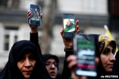 Para demonstran Iran mengacungkan ponsel dengan gambar mendiang MayjenQassem Soleimani, memprotes pembunuhan Soleimani, 4 Januari 2020. (Foto: Reuters)