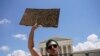 Seorang aktivis pendukung hak-hak aborsi mengacungkan poster saat demo di luar Mahkamah Agung AS di Washington DC, sehari setelah MA membatalkan preseden Roe vs Wade yang mengakui hak perempuan untuk melakukan aborsi, Sabtu, 25 Juni 2022. (Foto: Elizabeth Frantz/Reuters) 