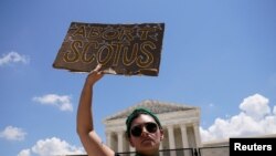 Seorang aktivis pendukung hak-hak aborsi mengacungkan poster saat demo di luar Mahkamah Agung AS di Washington DC, sehari setelah MA membatalkan preseden Roe vs Wade yang mengakui hak perempuan untuk melakukan aborsi, Sabtu, 25 Juni 2022. (Foto: Elizabeth Frantz/Reuters) 