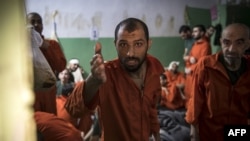 FILE - Men suspected of being affiliated with the Islamic State group gather in a prison cell in the northeastern Syrian city of Hasakah, Oct. 26, 2019.