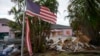 FILE - A tattered American flag flaps outside a home damaged by Hurricane Helene, ahead of the arrival of Hurricane Milton in Holmes Beach on Anna Maria Island, Florida, Oct. 8, 2024.