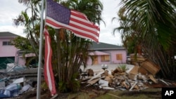 FILE - A tattered American flag flaps outside a home damaged by Hurricane Helene, ahead of the arrival of Hurricane Milton in Holmes Beach on Anna Maria Island, Florida, Oct. 8, 2024.