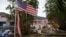 FILE - A tattered American flag flaps outside a home damaged by Hurricane Helene, ahead of the arrival of Hurricane Milton in Holmes Beach on Anna Maria Island, Florida, Oct. 8, 2024.