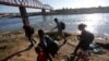 Para migran berjalan di sepanjang tepi sungai Rio Grande sebelum menyeberang dalam upaya mencari suaka ke AS, terlihat dari Piedras Negras, Meksiko, 29 September 2023. (Foto: REUTERS/Daniel Becerri)