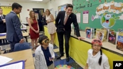 House Speaker Paul Ryan of Wis., right, and Rep. Carlos Curbelo, R-Fla., left, watch as students Christian Rubio, left foreground, and Jocelyn Zuniga, right foreground, explore the effect of friction on different surfaces, during a Science class at Caribbean Elementary School, Wednesday, Oct. 19, 2016, in Miami.