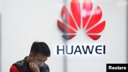 FILE - A staff member stands in front of a Huawei shop in Beijing, China, March 7, 2019. 