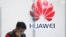 FILE - A staff member stands in front of a Huawei shop in Beijing, China, March 7, 2019. 