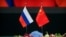 FILE - Russian, left, and Chinese flags sit on a table before a signing ceremony at the Great Hall of the People in Beijing, June 8, 2018. 