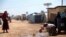 FILE - A refugee is seen scooping water from a puddle at a camp on the Syrian side of the border with Turkey, near the town of Atma, in Idlib province, Syria, April 19, 2020.
