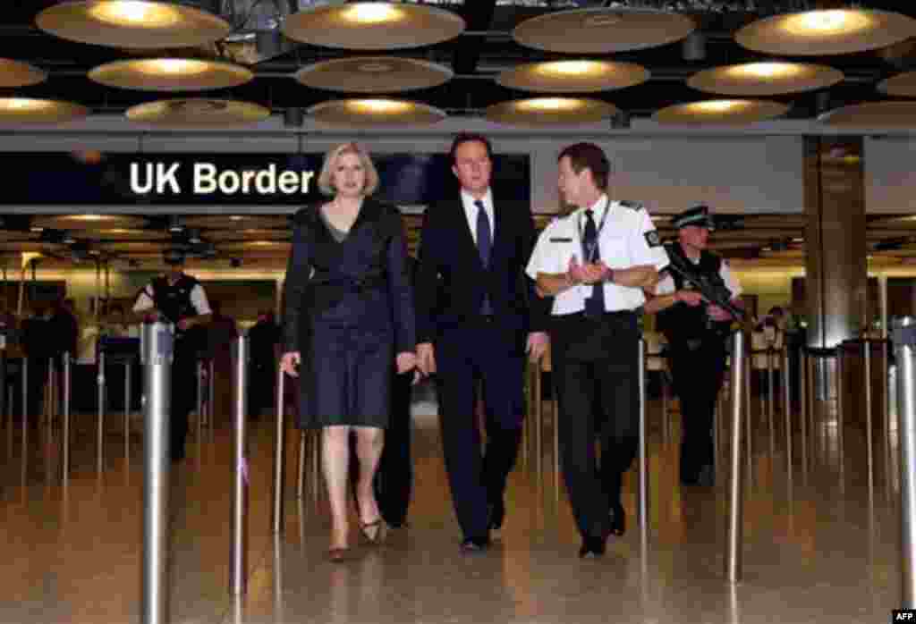 British Prime Minister David Cameron, center, and Home Secretary Theresa May, left, visit the UK Border Agency staff at Terminal 5 of Heathrow Airport, London where they were shown differences between fake and real passports Tuesday Nov. 23, 2010. Britain