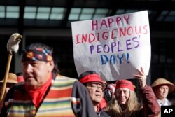 A sign is held aloft during an Indigenous Peoples Day march, Oct. 9, 2017, in Seattle. Native American people will celebrate their centuries-long history of resilience on Monday, Oct. 9, 2023, through ceremonies, dances and speeches.