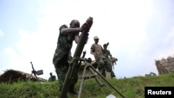  M23 rebel fighter loads an 82mm mortar bomb at their defense position in Karambi, eastern Democratic Republic of Congo (DRC) in north Kivu province, near the border with Uganda, July 12, 2012. 