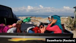 Perempuan beserta harta bendanya dievakuasi ke tempat yang lebih tinggi setelah tsunami melanda pantai Lolik dekat Palu, Sulawesi, 1 Oktober 2018. (Foto: REUTERS/Beawiharta)