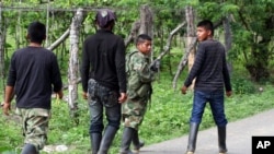 ARCHIVO - Rebeldes de las Fuerzas Armadas Revolucionarias de Colombia (FARC) abandonan el área después de bloquear una carretera en El Palo, en el estado sureño de Cauca, Colombia, el martes 4 de junio de 2013.