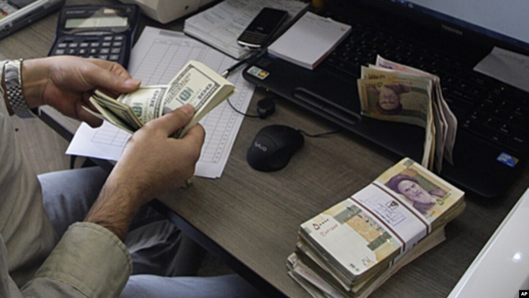 A currency exchange bureau worker counts US dollars, as Iranian bank notes are seen at right with portrait of late revolutionary founder Ayatollah Khomeini, in downtown Tehran, Iran. (file)