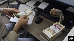 A currency exchange bureau worker counts US dollars, as Iranian bank notes are seen at right with portrait of late revolutionary founder Ayatollah Khomeini, in downtown Tehran, Iran. (file)