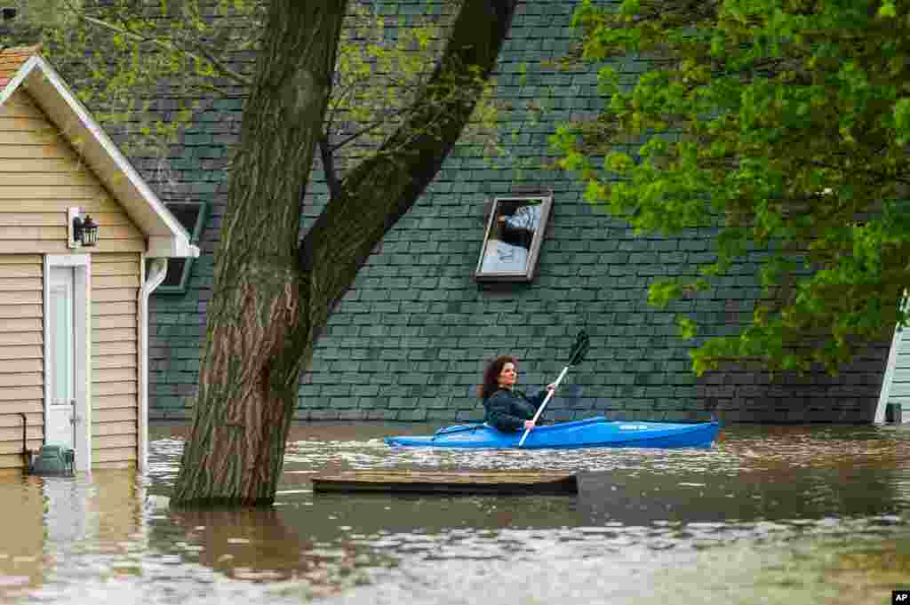 A woman use a kayak to assess the damage at homes in her neighborhood on Oakridge Road on Wixom Lake in Beaverton, Michigan. Rapidly rising water has overtaken dams and forced the evacuation of about 10,000 people. (Credit: Midland Daily News) 