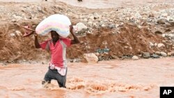 FILE - A man wades through a flooded river caused by last week's heavy rains caused by Tropical Cyclone Freddy in Phalombe, southern Malawi Saturday, March 18, 2023.