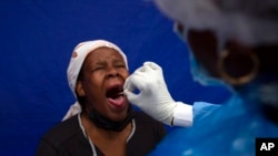 FILE - A throat swab is taken from a patient to test for COVID-19 at a facility in Soweto, South Africa, Dec. 2, 2021.