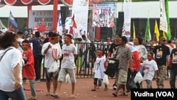 Sekelompok anak memakai atribut pasangan capres cawapres nomor urut 01 di tengah lokasi kampanye terbuka capres 01, Joko Widodo, di Solo, Selasa, 9 April 2019. (Foto: VOA/Yudha)