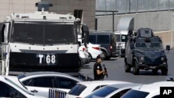 FILE - A police officer stands guard as an armored vehicle patrols outside a court building in Istanbul, Aug. 15, 2016. Authorities in the city of Konya on Thursday ordered the detention of 73 air force pilots alleged to have been part of a failed July coup.