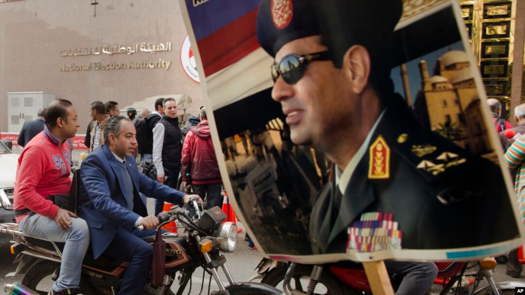 FILE - A supporter holds a poster showing President Abdel-Fattah el-Sissi in front of the National Elections Authority in Cairo, Egypt, Jan. 29, 2018. 