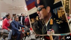 FILE - A supporter holds a poster showing President Abdel-Fattah el-Sissi in front of the National Elections Authority in Cairo, Egypt, Jan. 29, 2018. 