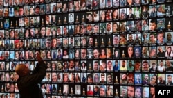 TOPSHOT - A visitor takes pictures of a giant screen of portraits of Israelis killed during the October 7 attacks by Hamas in southern Israel or those who died during the ongoing battles between Israel and Hamas in Gaza, at the National Library in Jerusalem, on January 25, 2024.