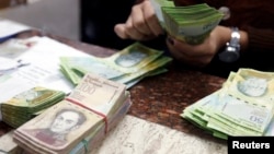 FILE - A cashier counts bolivars at a money exchange in Caracas, Venezuela, Feb. 24, 2015. 