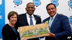 FILE - Barb Bennett, left, president/COO of Vulcan Inc, and U.S. Transportation Secretary Anthony Foxx, center, present the Smart City Challenge award to Columbus, Ohio, Mayor Andrew Ginther in Columbus, Ohio, June 23, 2016. 