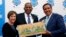FILE - Barb Bennett, left, president/COO of Vulcan Inc, and U.S. Transportation Secretary Anthony Foxx, center, present the Smart City Challenge award to Columbus, Ohio, Mayor Andrew Ginther in Columbus, Ohio, June 23, 2016. 