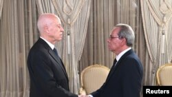 Presiden Tunisia Kais Saied (kiri) berjabat tangan dengan Perdana Menteri Tunisia Ahmed Hachani di Tunis, Tunisia, pada 1 Agustus 2023. (Foto: Tunisian Presidency/Handout via Reuters)