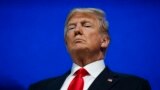 President Donald Trump listens as he is introduced to deliver a speech to the World Economic Forum.