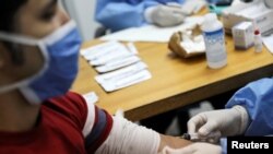 FILE PHOTO: Medical workers take blood samples from a man for a coronavirus disease (COVID-19) rapid test due to the COVID-19 outbreak in Caracas, Venezuela, April 15, 2020.