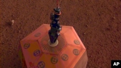 FILE - This photo, provided by NASA Jet Propulsion Laboratory, shows the new Mars lander placing a quake monitor on the planet’s dusty red surface. The unprecedented milestone occurred less than a month after Mars InSight’s touchdown. 