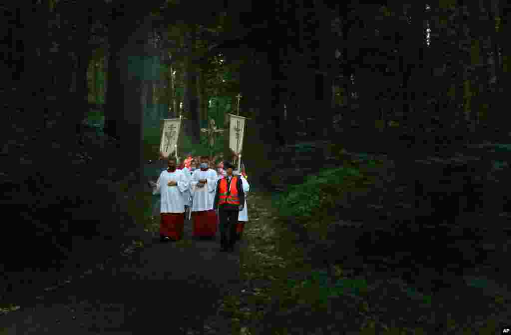 Believers walk through a forest near the pilgrimage church Maria Vesperbild during a light procession on Assumption Day, Aug. 15, 2020, in Ziemetshausen, Germany.