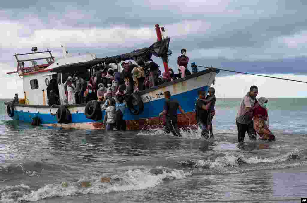 Local fisherman help Rohingya people as they arrive on Lancok Beach, North Aceh, Indonesia. 